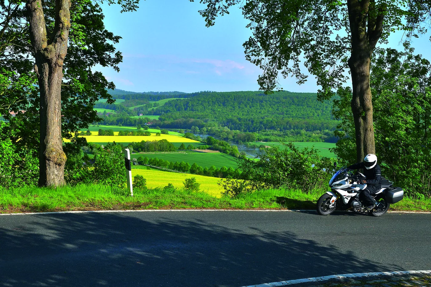 Motorrad auf einer Höhenstraße mit Blick über Rapsfelder und bewaldete Höhenzüge Motorrad auf einer Höhenstraße mit Blick über Rapsfelder und bewaldete Höhenzüge